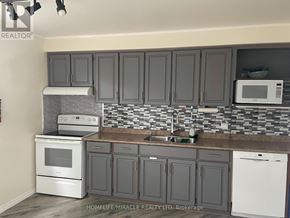 Barrie (Cundles East) apartment for rent - A kitchen with a white oven and microwave, and a sink with a faucet.