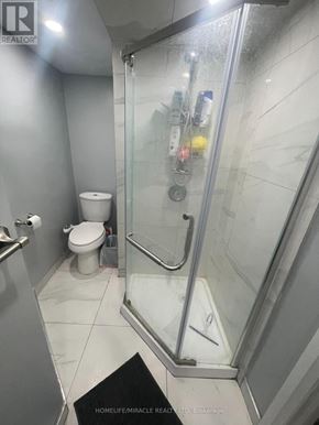 Barrie (Cundles East) apartment for rent - A bathroom with a toilet, a glass shower stall, and a mat on the floor.