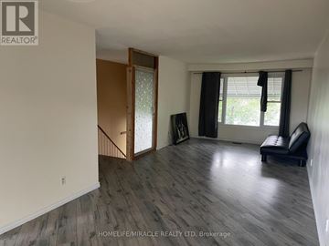 Barrie (Cundles East) apartment for rent - A living room with a black leather chair and a wooden door leading to a staircase.