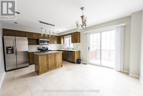 Markham (Berczy) townhouse for rent - A large red brick house with a black garage door.