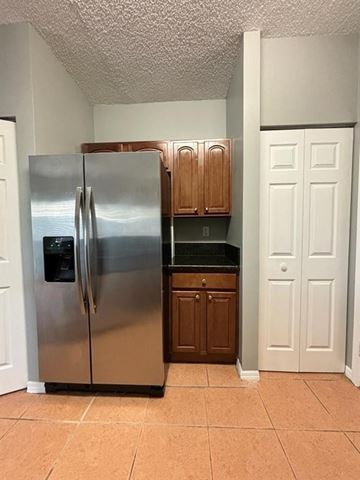 Miramar apartment for rent - A stainless steel refrigerator in a kitchen with brown cabinets.