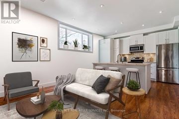 Toronto (Stonegate-Queensway) apartment for rent - A modern living room with a grey sofa, a wooden coffee table, and a kitchen area in the background.