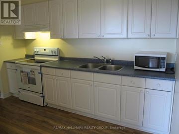 Ottawa condo for rent - A kitchen with white cabinets and a black countertop.
