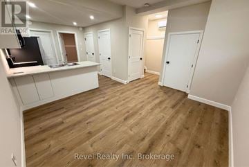Woodstock (Woodstock - North) apartment for rent - A room with wooden flooring and white walls, with a kitchen area on the left and a door on the right.