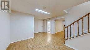 Toronto (Agincourt South-Malvern West) apartment for rent - A spacious room with wooden flooring and white walls, featuring a staircase with wooden railings.