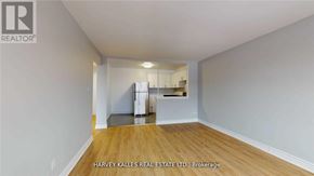 Toronto (Keelesdale-Eglinton West) apartment for rent - A spacious room with wooden flooring and white walls, with a kitchen area visible in the background.