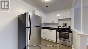 Toronto (Keelesdale-Eglinton West) apartment for rent - A kitchen with a black fridge, stove and white cabinets.