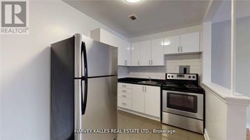 Toronto (Keelesdale-Eglinton West) apartment for rent - A kitchen with a black fridge, stove and white cabinets.
