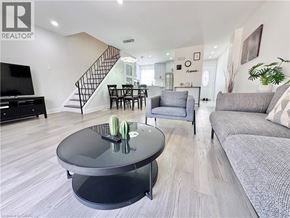 Kitchener townhouse for rent - A living room with a grey couch, a black coffee table, and a staircase.