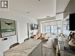 Kitchener apartment for rent - A modern kitchen with a marble countertop and a flat-screen TV mounted above the fridge.