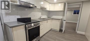 Kitchener apartment for rent - A kitchen with a black stove top oven and white cabinets.