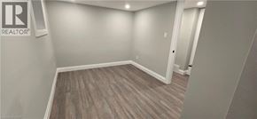 Kitchener apartment for rent - A room with a wooden floor and a Realtor sign on the wall.
