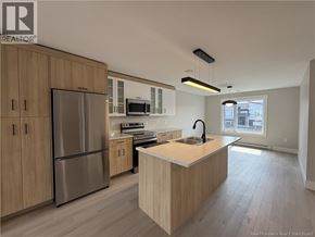 Shediac townhouse for rent - A kitchen with wooden cabinets and a stainless steel refrigerator.