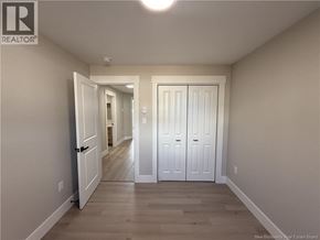 Shediac townhouse for rent - A hallway with white doors and wooden floors.