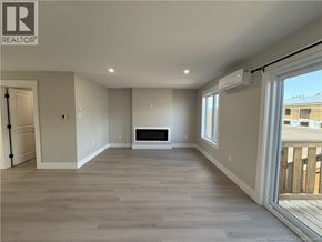 Shediac townhouse for rent - A spacious room with a fireplace and a sliding glass door.