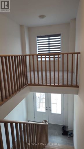 Welland (Dain City) apartment for rent - A staircase with wooden railings leads to a door with a window above it.