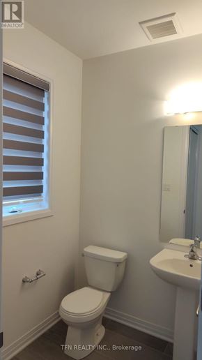 Welland (Dain City) apartment for rent - A white toilet sits next to a sink in a small bathroom.