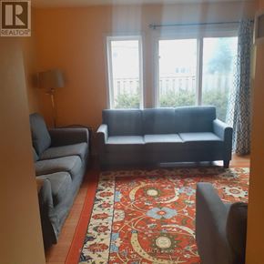 Kitchener townhouse for rent - A living room with a grey couch, a grey chair, and a red patterned rug.