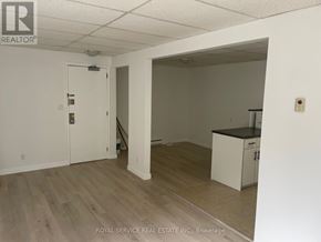 Cobourg multi-family for rent - A white room with a door and a kitchenette.