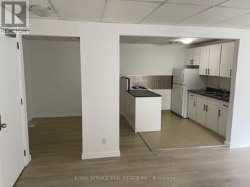 Cobourg multi-family for rent - A kitchen area with white cabinets and a refrigerator.