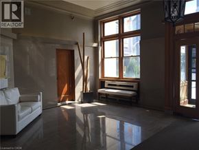 Kitchener condo for rent - A realtor logo is on the wall in a spacious room.