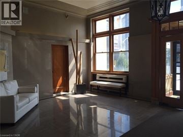Kitchener condo for rent - A realtor logo is on the wall in a spacious room.