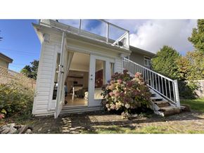 White Rock apartment for rent - A small white house with a glass door and a staircase leading to the entrance.