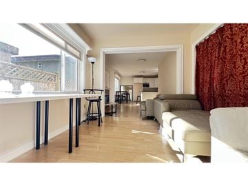 White Rock apartment for rent - A living room with a white couch and a dining table with chairs.