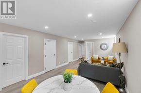 Barrie (Little Lake) apartment for rent - A living room with a grey couch, a white table, and a clock on the wall.