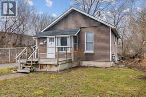 Hamilton apartment for rent - A house with a brown siding and a white door is surrounded by a grassy area.