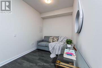 Toronto (Waterfront Communities) condo for rent - A living room with a grey couch and a round mirror on the wall.