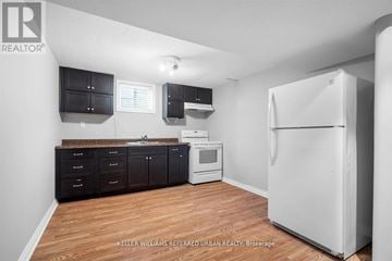 Toronto (Centennial Scarborough) apartment for rent - A kitchen with a white refrigerator, black cabinets, and a wooden floor.