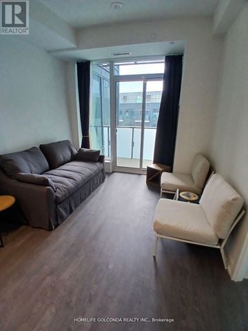 Toronto (Newtonbrook East) condo for rent - A living room with a black couch and a white chair.