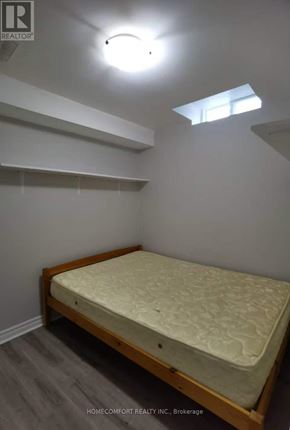 Toronto (Agincourt North) apartment for rent - A bedroom with a bed, wooden headboard, and a skylight.