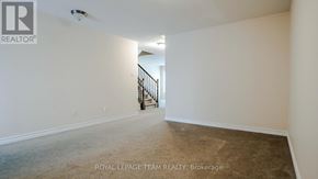Ottawa townhouse for rent - A spacious room with a carpeted floor and a staircase in the background.