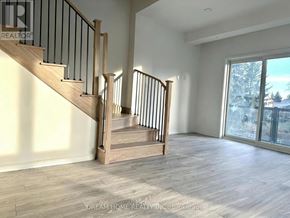 Newmarket (Glenway Estates) townhouse for rent - A spacious room with a staircase and a view of a snowy landscape outside the window.