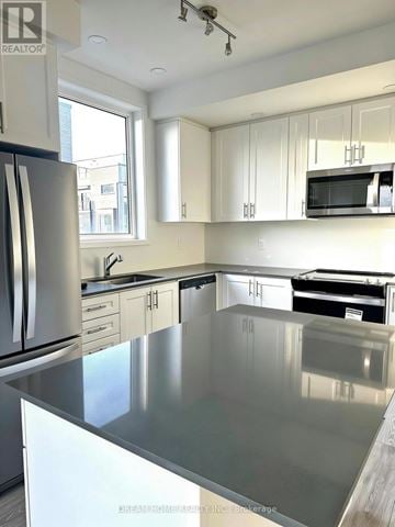 Newmarket (Glenway Estates) townhouse for rent - A kitchen with a stainless steel counter top and white cabinets.