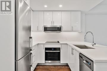Ottawa condo for rent - A modern kitchen with white cabinets and stainless steel appliances.