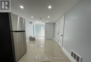 Toronto (Wexford-Maryvale) apartment for rent - A spacious kitchen with a refrigerator and a dining area with a table and chairs.