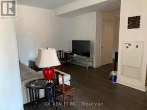 Toronto (Bay Street Corridor) condo for rent - A living room with a couch, a chair, a table with a lamp and a television.