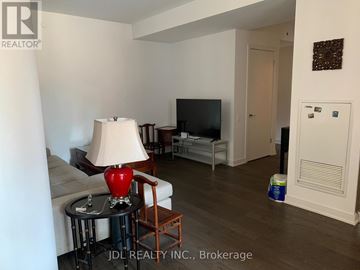 Toronto (Bay Street Corridor) condo for rent - A living room with a couch, a chair, a table with a lamp and a television.