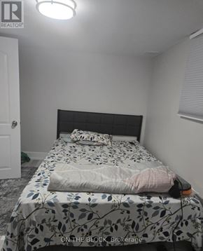 Toronto (Eglinton East) apartment for rent - A bedroom with a bed covered in a leaf patterned sheet.