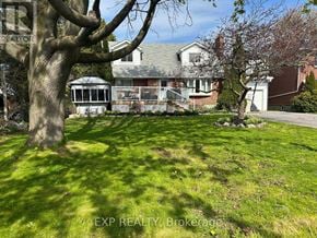 Cobourg apartment for rent - A tree stands in a yard in front of a house.