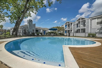 Houston apartment for rent - A swimming pool surrounded by a wooden deck and a fence.