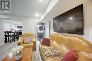 Mississauga (Streetsville) condo for rent - A living room with a brown leather couch and a flat screen TV mounted on the wall.