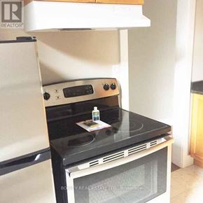 Toronto (Cabbagetown-South St. James Town) townhouse for rent - A black stove top oven with a white refrigerator in the background.