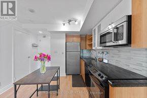 Toronto (Waterfront Communities) condo for rent - A modern kitchen with a wooden table and a vase of flowers on it.
