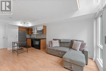 Toronto (Waterfront Communities) condo for rent - A living room with a grey couch and a black table.