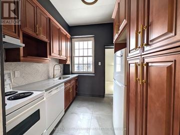 Prince Edward County (Picton Ward) fourplex for rent - A kitchen with dark wood cabinets and white appliances.