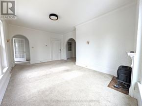 Prince Edward County (Picton Ward) fourplex for rent - A spacious room with a carpeted floor and a heater on.